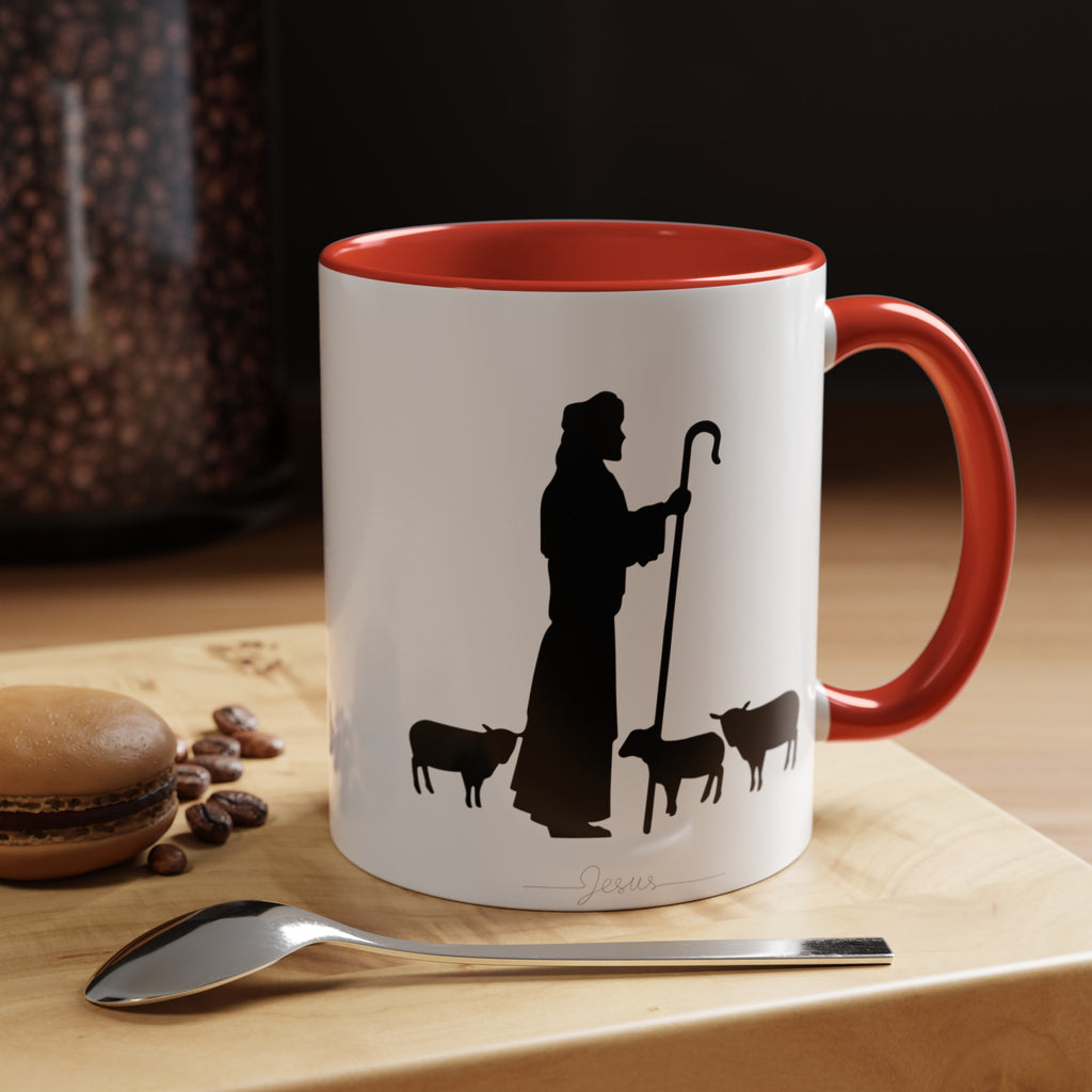 Front of the White Mug with Red Interior on Wood Table: "White ceramic mug with a vibrant red interior, showcasing a black ink illustration of Jesus and sheep on the front. Set on a wooden table, this accent mug is available in 11oz and 15oz sizes, perfect for a faith-filled start to your day.