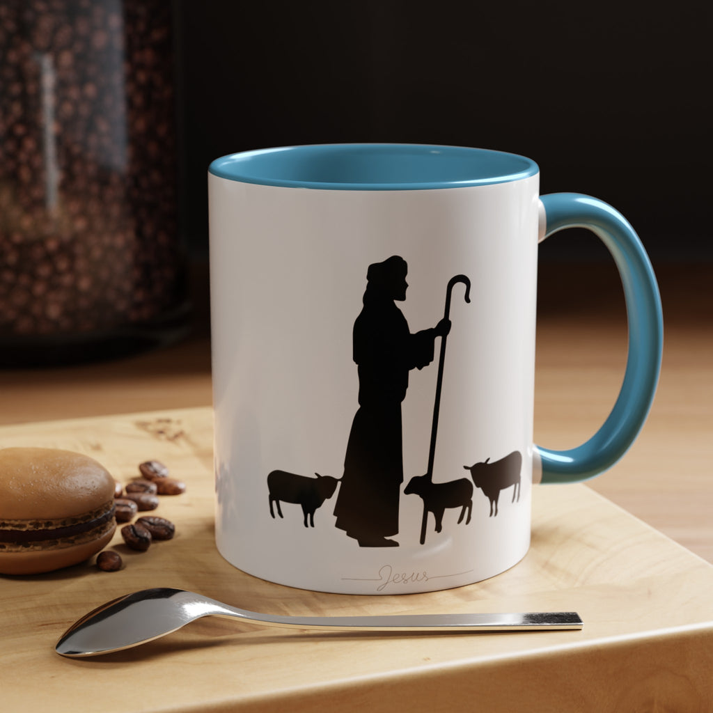Front of the White Mug with Light Blue Interior on Wood Table: "White ceramic coffee mug with a light blue interior, featuring a serene black ink design of Jesus and sheep. Pictured on a wood table, this 11oz or 15oz mug adds a peaceful touch to your daily coffee or tea ritual.