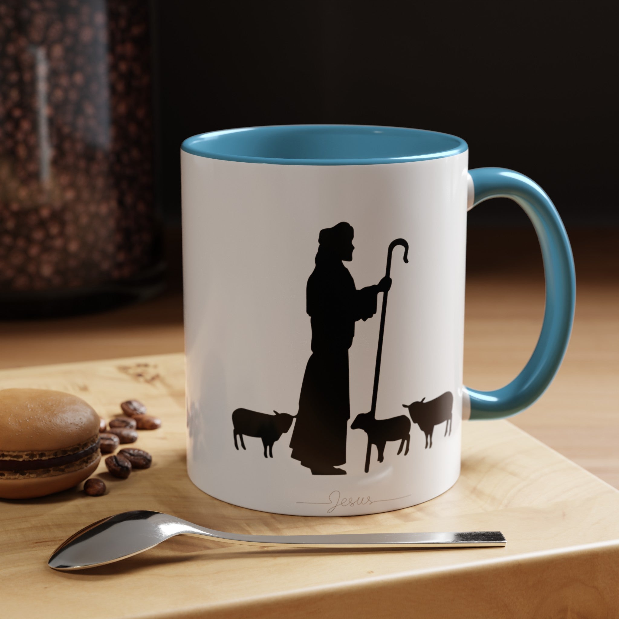 Front of the White Mug with Light Blue Interior on Wood Table: "White ceramic coffee mug with a light blue interior, featuring a serene black ink design of Jesus and sheep. Pictured on a wood table, this 11oz or 15oz mug adds a peaceful touch to your daily coffee or tea ritual.