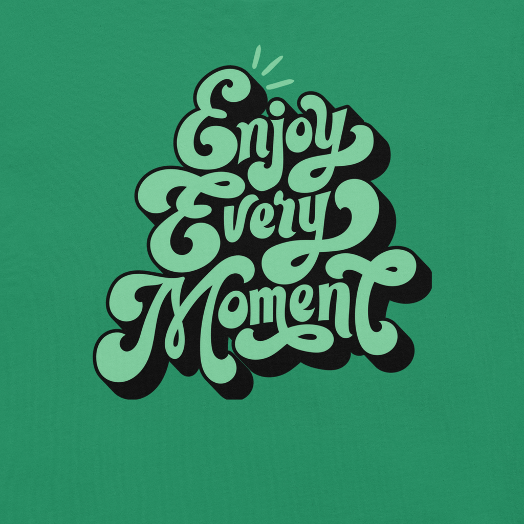 Close-up of 'Enjoy Every Moment' graffiti script on a green T-shirt, highlighting the intricate design and bold lettering on the soft, durable fabric.