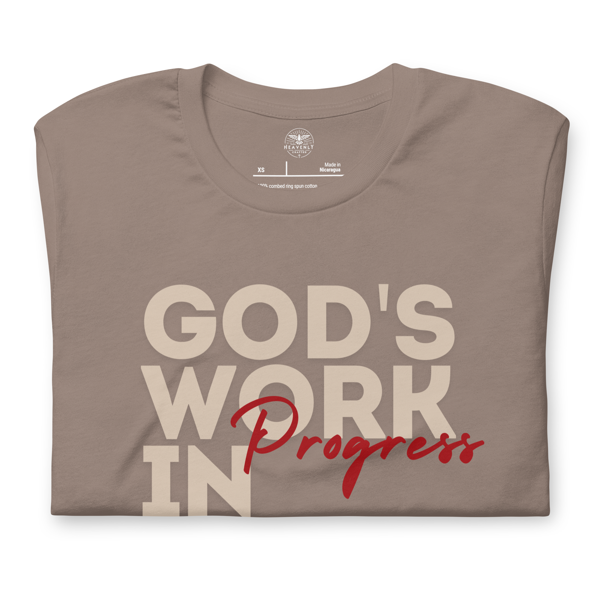 Folded Tan T-shirt by Heavenly Crafted with 'God's Work in Progress' in bold text. A soft, comfortable tee offering a daily reminder of personal growth and God's plan, inspired by Philippians 1:6.