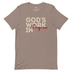 Front view of Heavenly Crafted's 'God's Work in Progress' T-shirt in Tan, showcasing the inspirational text design in bold lettering. A reminder of faith and growth inspired by Philippians 1:6. Shirt laid out natrually