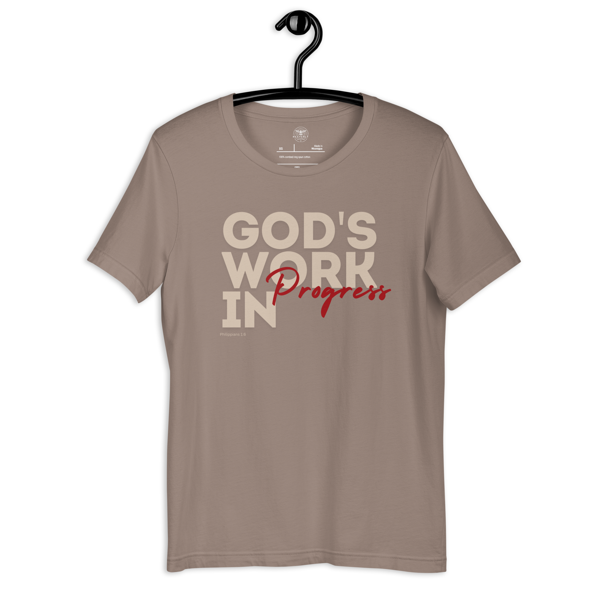 Brand and care instructions label inside Heavenly Crafted's 'God's Work in Progress' T-shirt in Tan. Hangs on a black hanger. Displays high-quality fabric details and care guidelines to maintain this soft, durable tee.