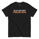 Flat lay of the black 'Be Still And Know' T-shirt with Psalm 46:10 text. Showcasing a minimalist design, this tee offers a serene and inspirational message, perfect for daily wear. Made for comfort and spiritual reflection, it's a versatile addition to any faith-based wardrobe.