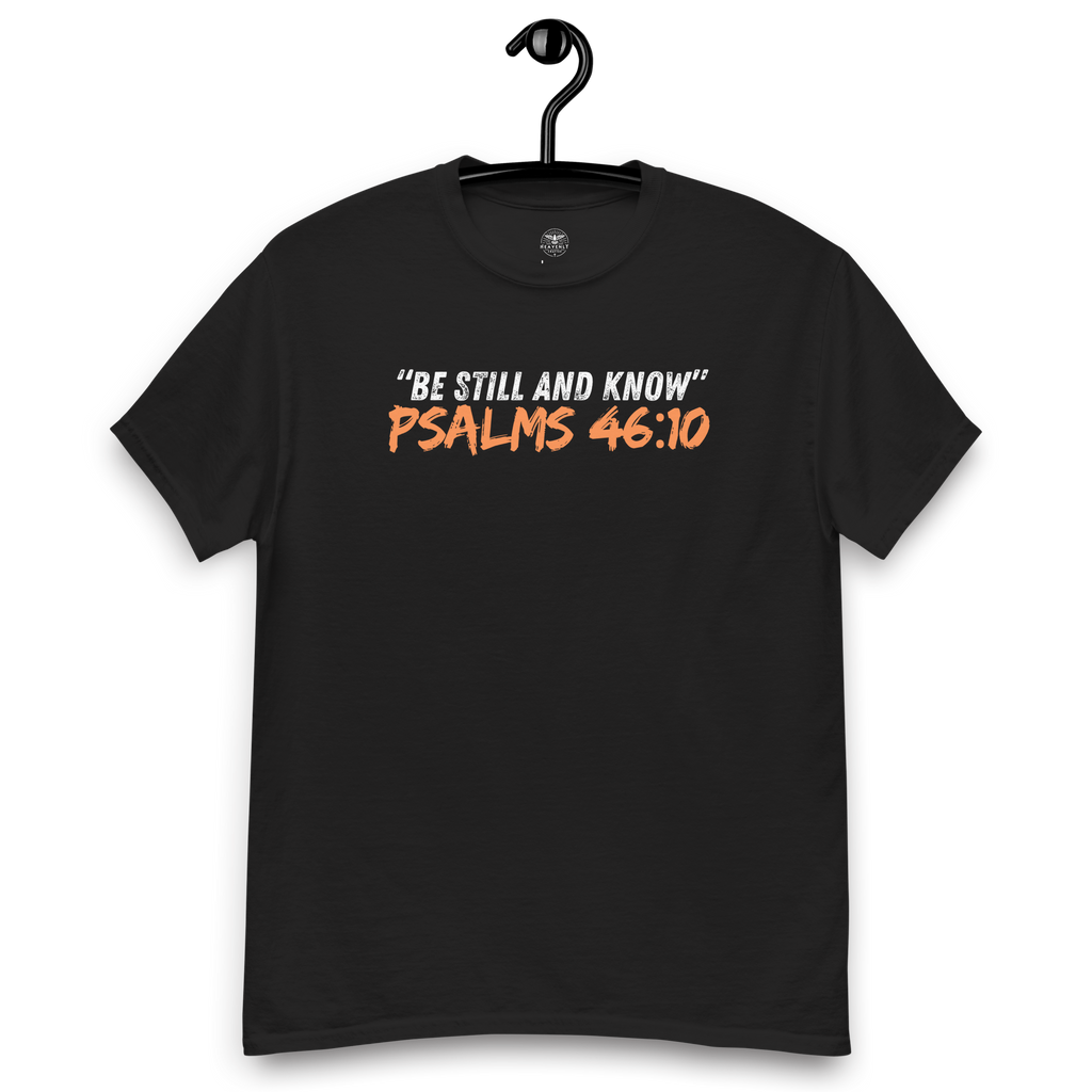 Front view of the black 'Be Still and Know' T-shirt on a wooden hanger, featuring Psalm 46:10. This faith-inspired tee offers a calming design, perfect for daily wear, encouraging peace and reflection. Crafted for comfort and style, it's an ideal addition to any spiritual wardrobe.