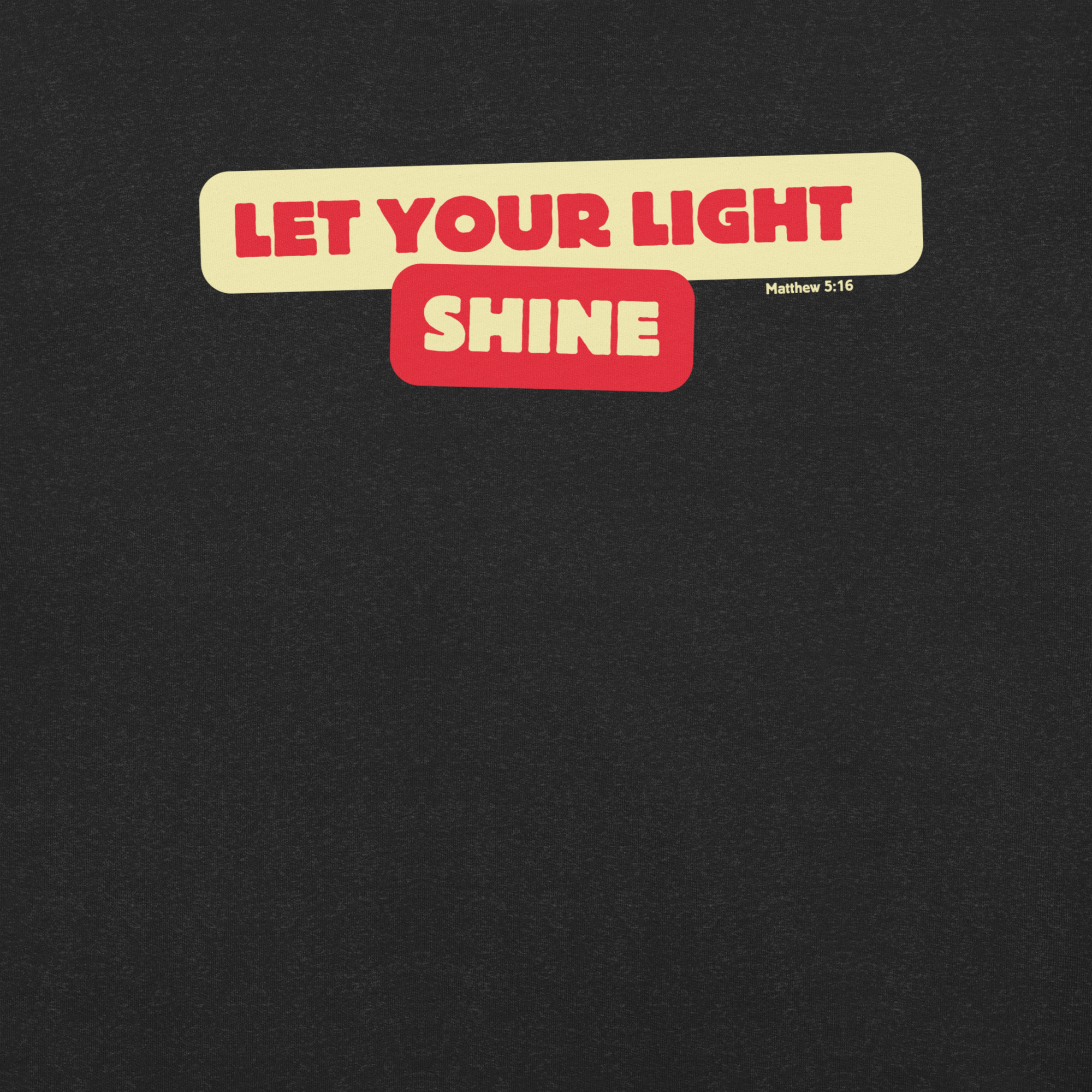 Close-up of the 'Let Your Light Shine' bold bubble text on a Black Heather T-shirt. Showcasing the inspirational design inspired by Matthew 5:16, this detailed view highlights the shirt's message and soft, high-quality fabric.