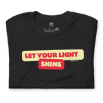 Folded Black Heather T-shirt with 'Let Your Light Shine' in bold yellow script lettering. This inspirational tee, made from soft, breathable cotton, conveys a message of faith and positivity.