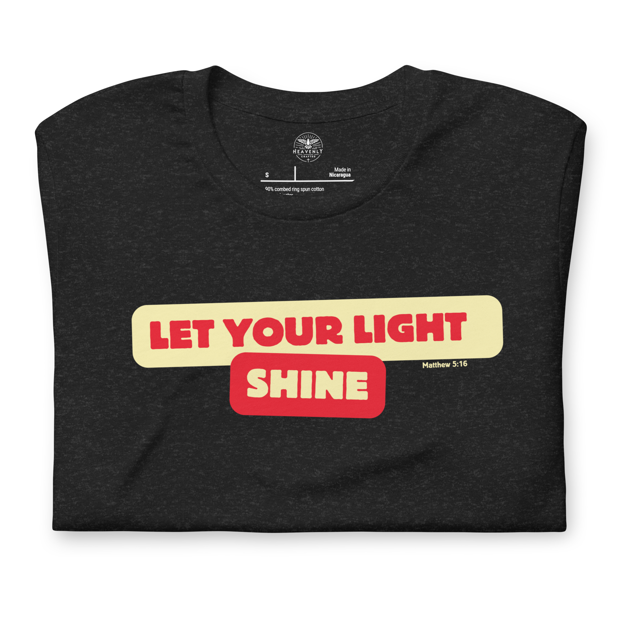 Folded Black Heather T-shirt with 'Let Your Light Shine' in bold yellow script lettering. This inspirational tee, made from soft, breathable cotton, conveys a message of faith and positivity.