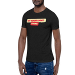 Model wearing the 'Let Your Light Shine' T-shirt in Black Heather, shown from a three-quarter view. Features bold yellow script lettering, inspired by Matthew 5:16, on soft, breathable cotton for a comfortable and stylish expression of faith.