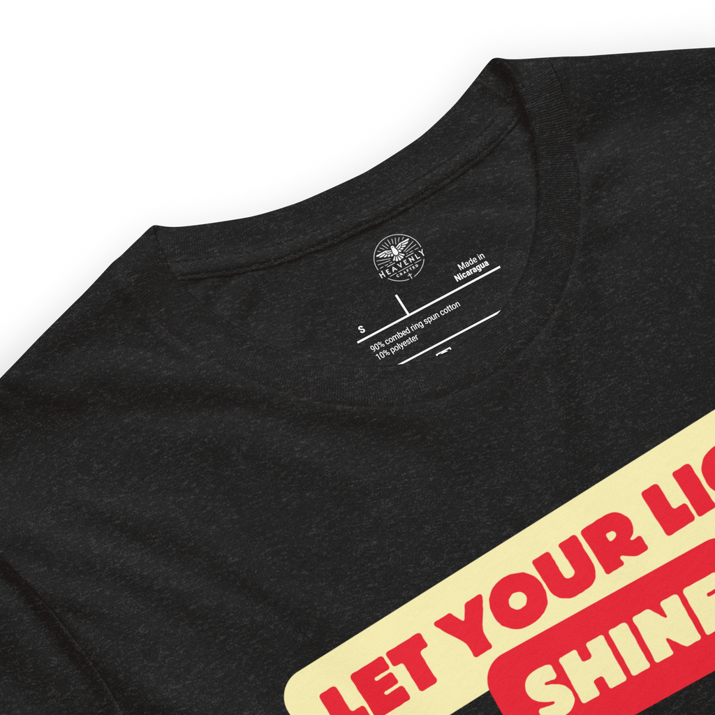 Logo stamp inside the 'Let Your Light Shine' T-shirt in Black Heather, displaying brand details and care instructions. Highlights the quality craftsmanship and durability of this faith-inspired apparel.