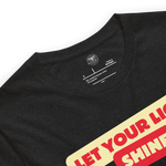 Logo stamp inside the 'Let Your Light Shine' T-shirt in Black Heather, displaying brand details and care instructions. Highlights the quality craftsmanship and durability of this faith-inspired apparel.