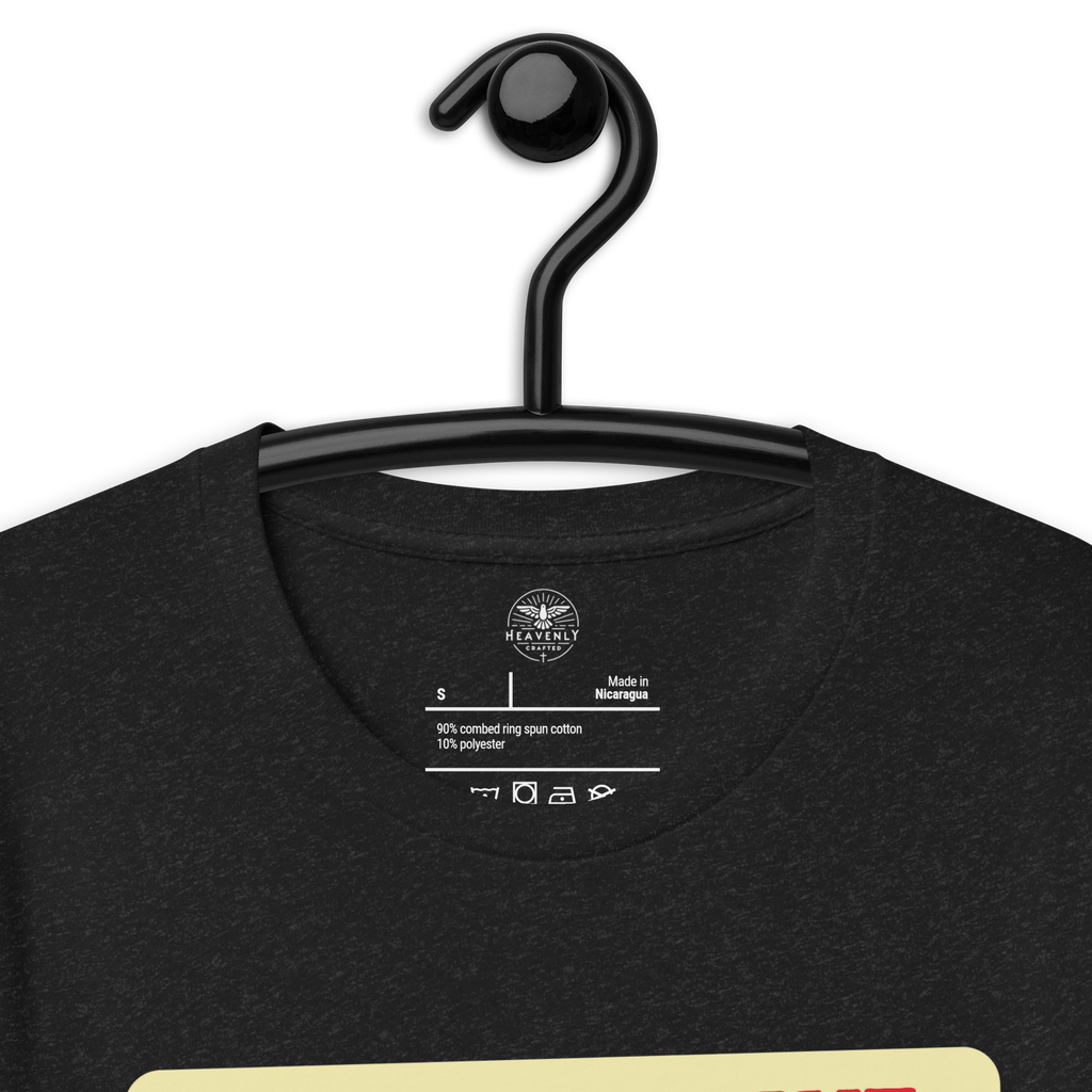 Logo stamp inside the 'Let Your Light Shine' T-shirt in Black Heather, displayed on a hanger, showing brand details and care instructions. Highlights the high-quality, durable construction of this faith-inspired garment.