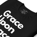 "Logo stamp inside 'Grace Upon Grace' T-shirt, showing brand and care instructions. Folded