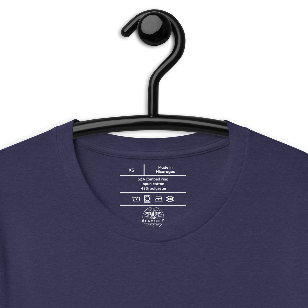 "Inside label of 'Hope Anchors the Soul' T-shirt, showing care instructions and fabric details, "Heather Midnight Navy 'Hope Anchors the Soul' T-shirt on wooden hanger.