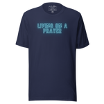 Main display mockup of 'Living on a Prayer' neon T-shirt in a shop setting, highlighted under soft lighting.