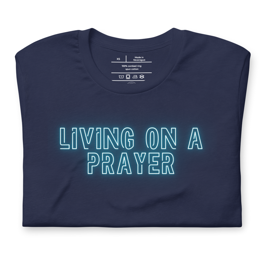 Folded navy T-shirt with 'Living on a Prayer' in vibrant neon lights script.