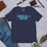 Main display mockup of 'Living on a Prayer' neon T-shirt in a shop setting, highlighted under soft lighting.