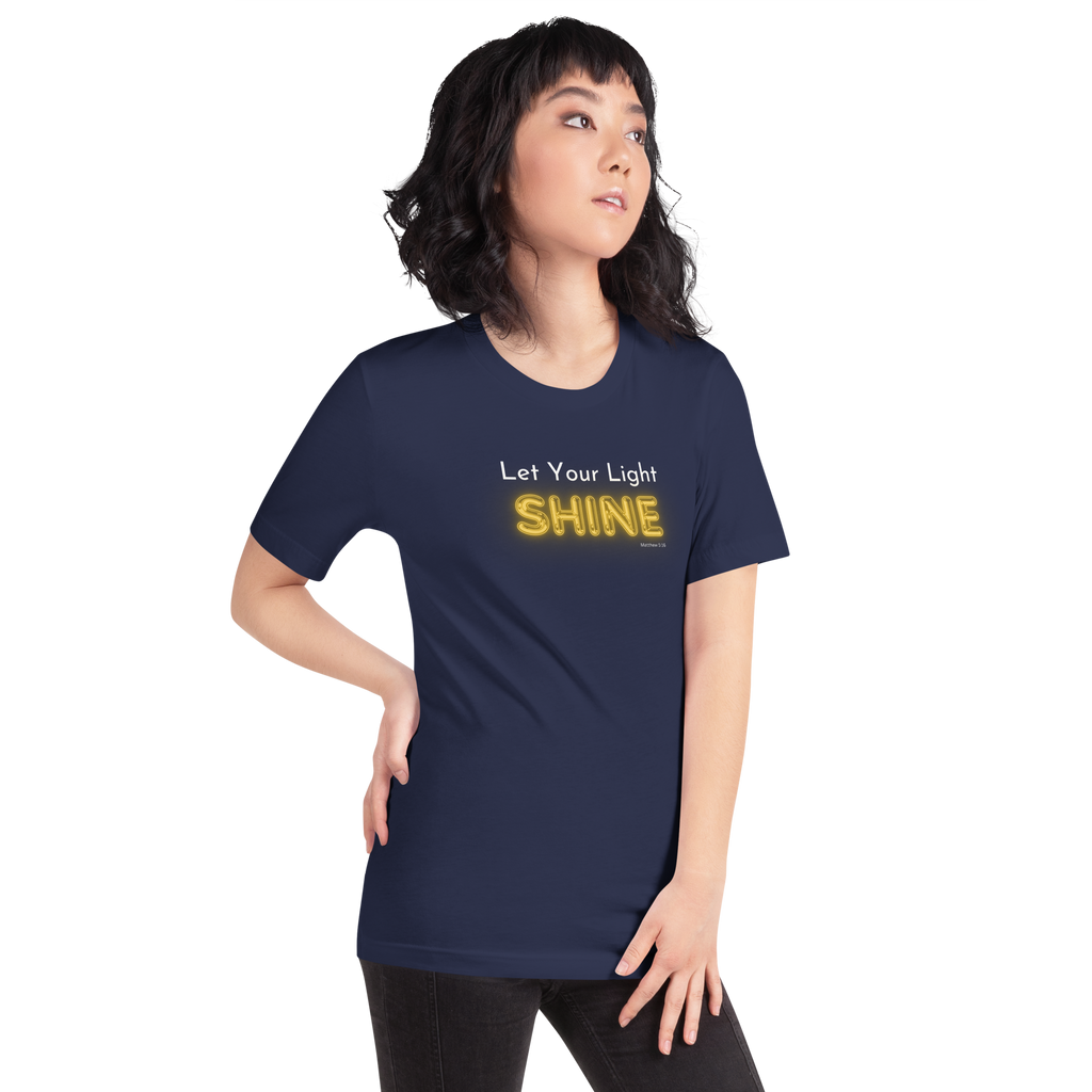 Model wearing 'Let Your Light Shine' T-shirt in navy, three-quarter view, glowing text.