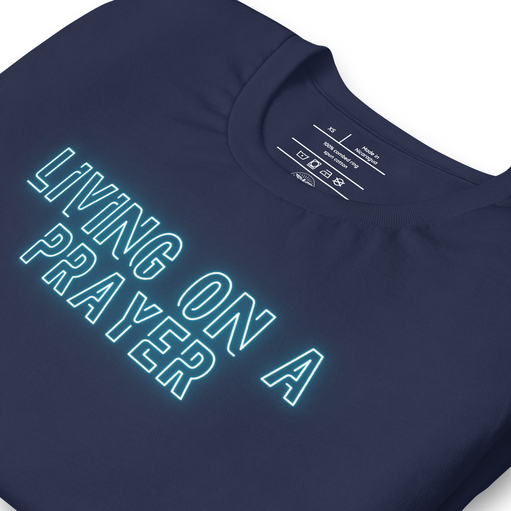 Close-up of neon 'Living on a Prayer' text on navy T-shirt, glowing effect.