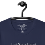 Logo stamp inside 'Let Your Light Shine' T-shirt in navy, showing brand and care instructions on a hanger