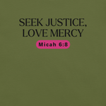 Close-up of the logo on the 'Army of Faith' T-shirt in Army Green, displaying the intricate black text and pink button-like design. Showcasing brand details and care instructions, this design draws inspiration from Ephesians 6:11, emphasizing the shirt's message of strength and protection.