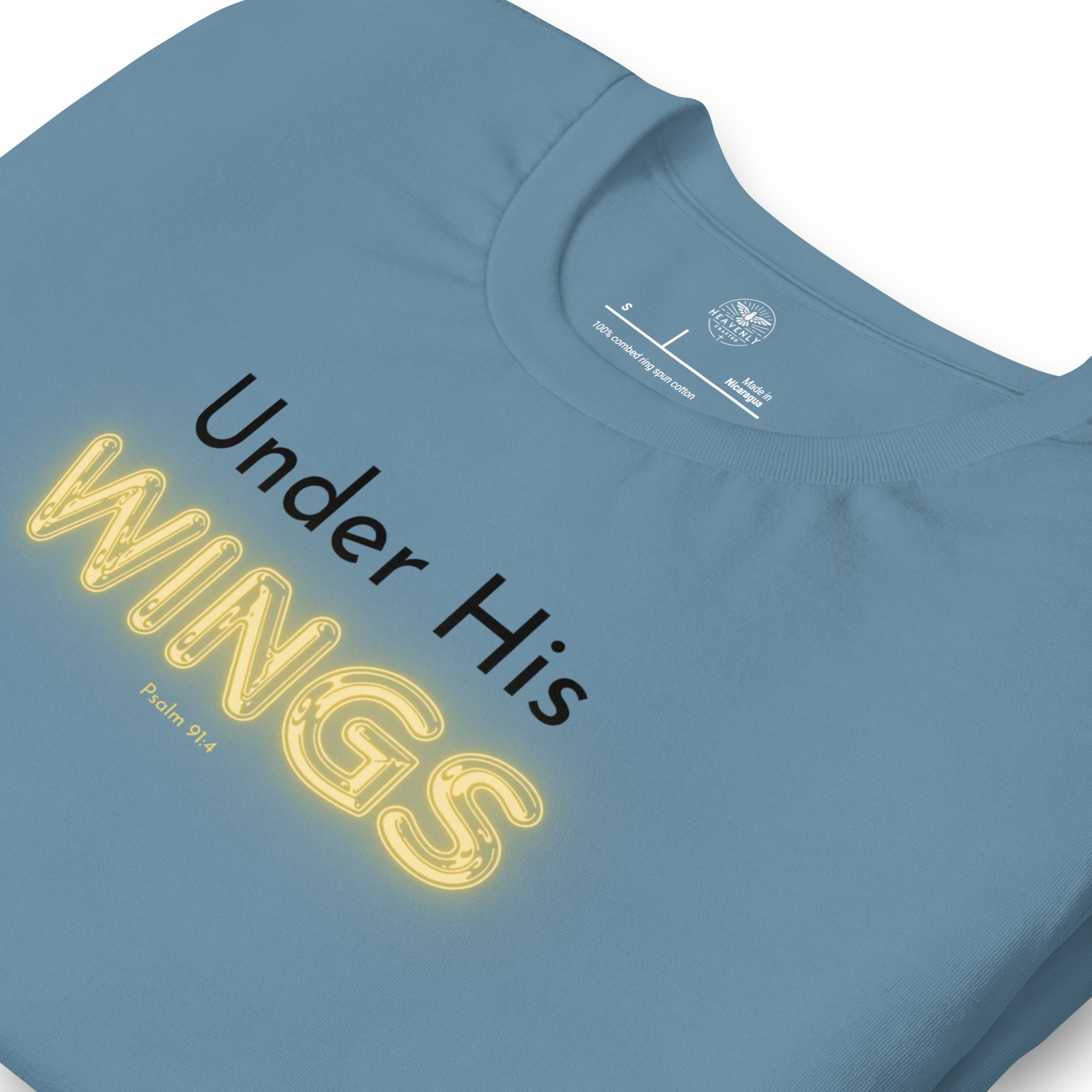 Folded navy blue T-shirt with 'Under His' in black text and 'Wings' in glowing yellow. "Logo stamp inside 'Under His Wings' T-shirt in navy blue, showing brand and care instructions.