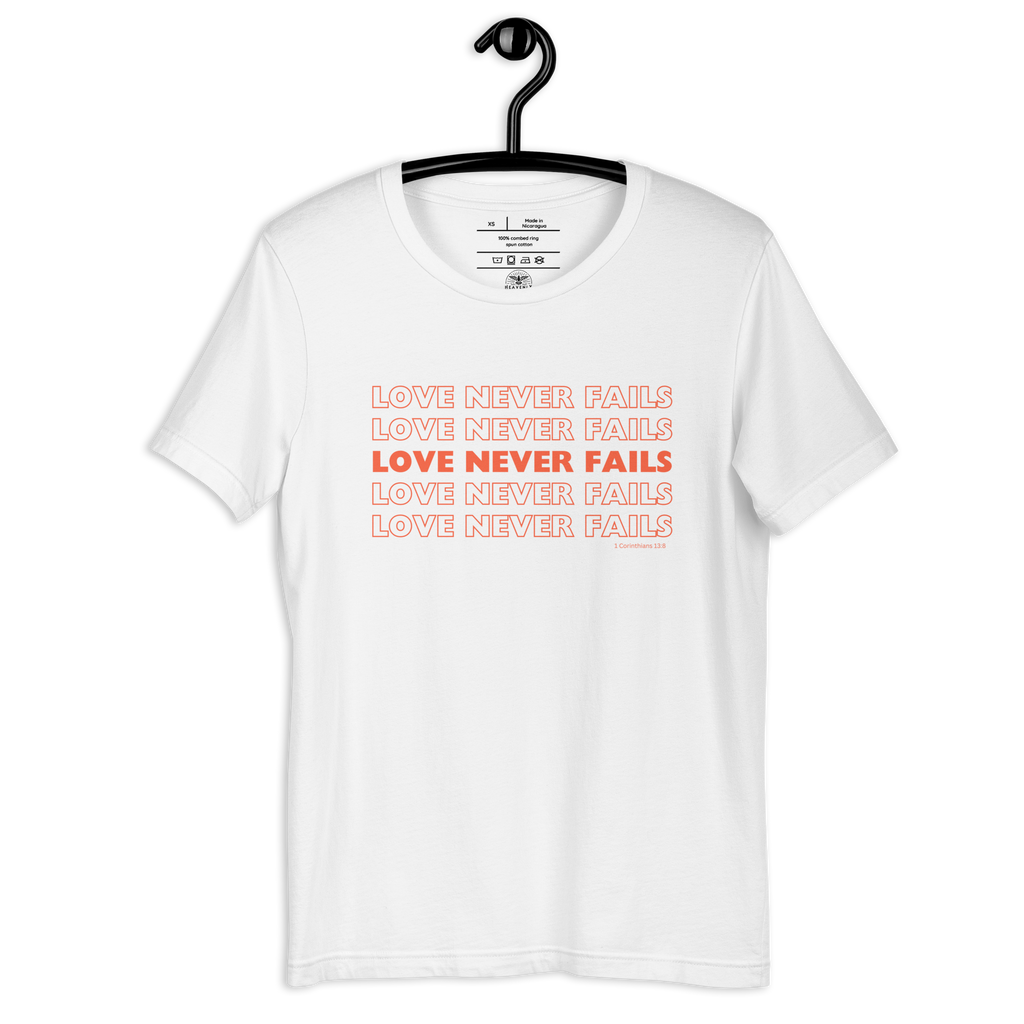 White 'Love Never Fails' T-shirt on wooden hanger.
